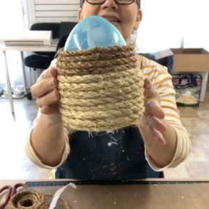 Tracy holding up rope wrapped around a large Easter egg